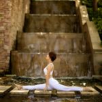 woman doing a split on stepping stones over a river