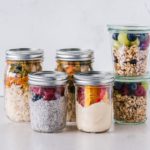 six fruit cereals in clear glass mason jars on white surface