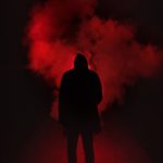 silhouette of man standing against black and red background