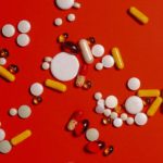 different medication pills and capsules on red background