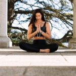 woman in black tank top and black pants sitting on concrete floor