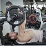 strong sportsman doing bench press during workout in modern gym