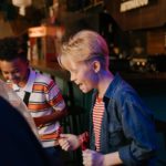 man in blue denim jacket holding a woman in white and red stripe shirt