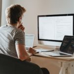man sitting in front of three computers