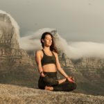 woman in black sports bra and black pants sitting on rock