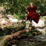 man in red dress shirt sitting on tree log