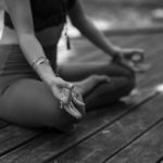 grayscale photo of woman in black tank top and white shorts sitting on wooden floor