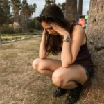 photo of a woman crouching while her hands are on her head