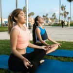 women meditating in the park with yoga mats