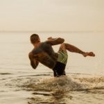 a man practicing kick boxing while on the beach