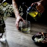 a person pouring yellow liquid in the glass