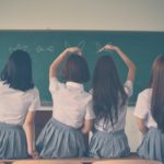 photo of four girls wearing school uniform doing hand signs