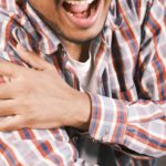 close up photo of an aching man holding his shoulder