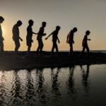 group of children walking near body of water silhouette photography